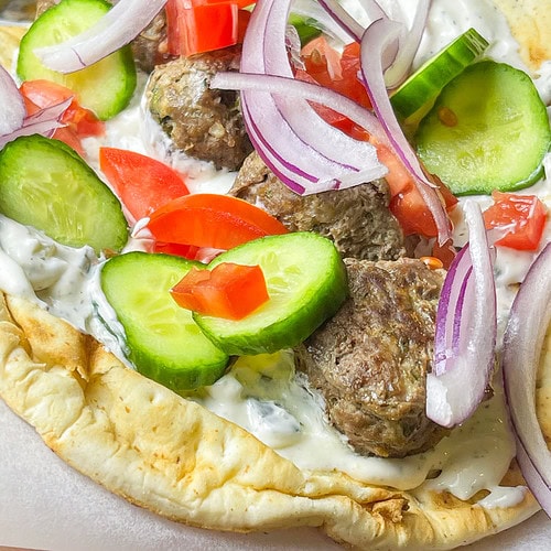 An easy and quick weeknight dinner, Greek Inspired Sheet Pan Meatballs are juicy meatballs bursting with familiar Greek flavors, baked on a sheet pan for fast clean, the perfect meal to make on a busy night. These Greek Meatballs are made with ground beef (or substitute lamb, chicken or turkey), garlic, red onion, and aromatic herbs like oregano, parsley, and mint. They’re tender, juicy, and packed with Mediterranean flair. Perfect for serving with tzatziki sauce, pita bread, or a fresh Greek salad, these meatballs are versatile enough for appetizers or a main meal. Shake up your usual dinner!