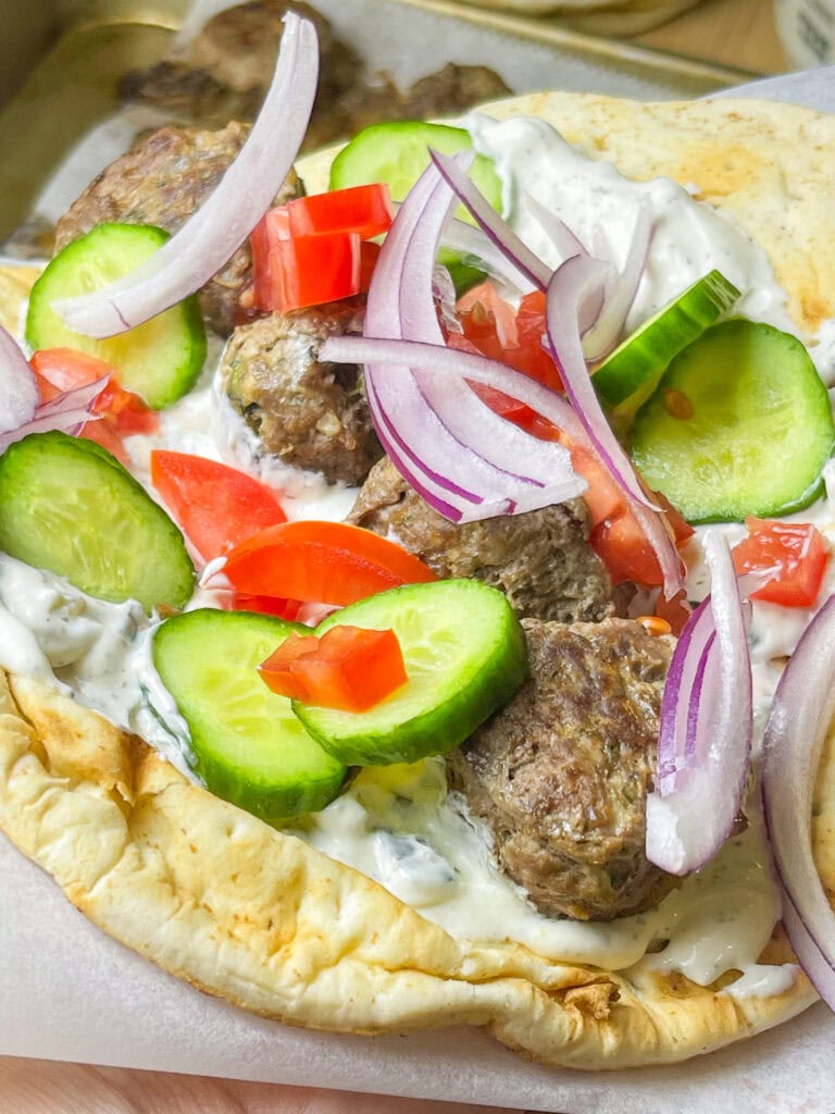 An easy and quick weeknight dinner, Greek Inspired Sheet Pan Meatballs are juicy meatballs bursting with familiar Greek flavors, baked on a sheet pan for fast clean, the perfect meal to make on a busy night. These Greek Meatballs are made with ground beef (or substitute lamb, chicken or turkey), garlic, red onion, and aromatic herbs like oregano, parsley, and mint. They’re tender, juicy, and packed with Mediterranean flair. Perfect for serving with tzatziki sauce, pita bread, or a fresh Greek salad, these meatballs are versatile enough for appetizers or a main meal. Shake up your usual dinner!