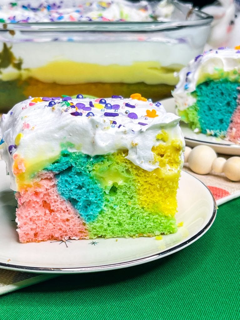 This colorful Easter Poke Cake is sure to delight on your Easter table! This cake is so easy to prepare but looks like an absolute show stopper. All you need is a box of cake mix, food coloring, pudding mix and cool whip for the brightest dessert to WOW your guests.