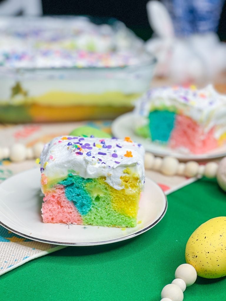 This colorful Easter Poke Cake is sure to delight on your Easter table! This cake is so easy to prepare but looks like an absolute show stopper. All you need is a box of cake mix, food coloring, pudding mix and cool whip for the brightest dessert to WOW your guests.