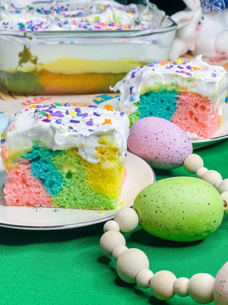 This colorful Easter Poke Cake is sure to delight on your Easter table! This cake is so easy to prepare but looks like an absolute show stopper. All you need is a box of cake mix, food coloring, pudding mix and cool whip for the brightest dessert to WOW your guests.