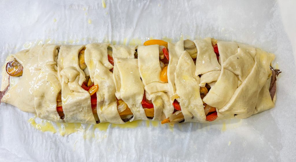 This Cheesesteak Crescent Roll Braid is perfect for any party, on game day, or for an easy weeknight dinner. It starts with a sheet of flaky crescent dough and is filled with roast beef, provolone cheese, horseradish sauce and sauteed veggies. A crowd pleaser, for sure!