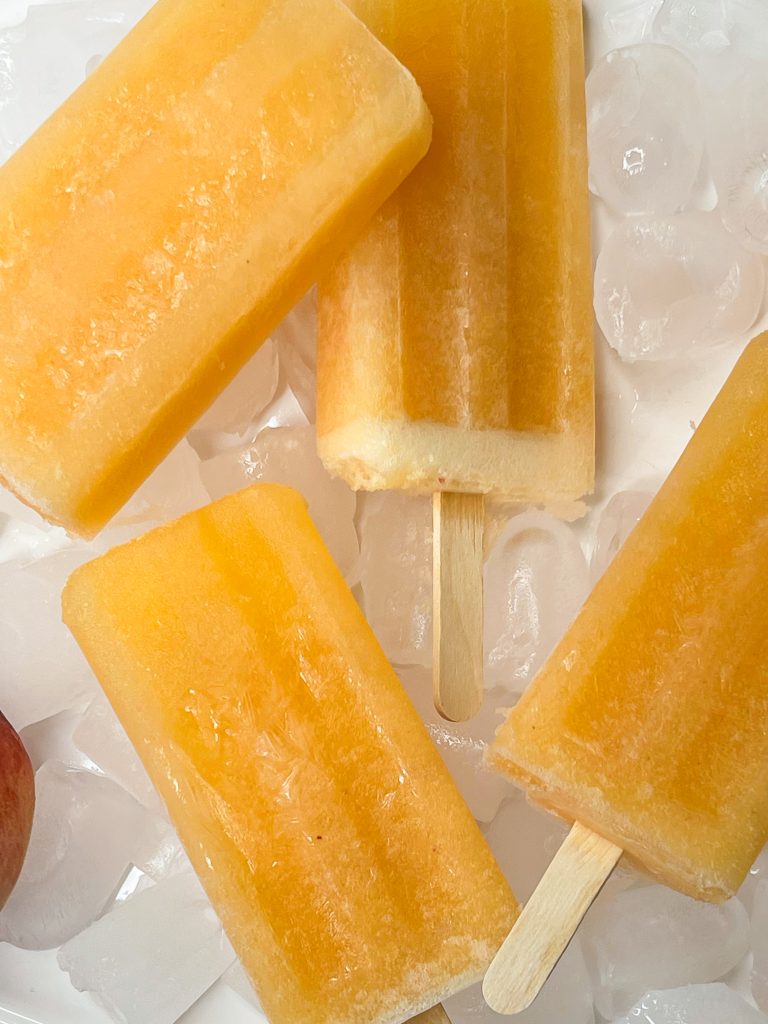 These adult only winesicles are made with 3 simple ingredients blended together-peaches (fresh, frozen, or canned), orange juice, and white wine. They are quick and simple to make and are my favorite way to cool off in the summer. Picture it- the hot sun, a pool, and a cold peach winesicle. Yes, please!