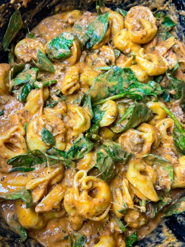 The whole family is going to love this easy weeknight Crock Pot Cheesy Tortellini dinner. It's creamy, rich and filling with tortellini, cream cheese, a hearty meat sauce and spinach.