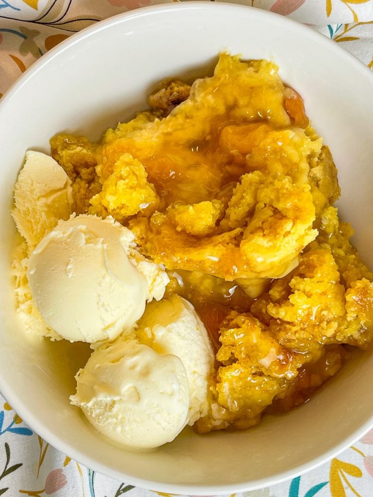 You'll love this Crock Pot Peach Cobbler because it's only 3 simple ingredients, it's the perfect dessert for any occasion, and it's a cinch to put together. This crock pot peach cobbler is my go-to dessert for a potluck for family gathering when I'm short on time. It's only 3 ingredients! The ingredients are peach pie filling, yellow cake mix, and butter. That's it! It takes literally 5 minutes to prep, it's inexpensive to make and it feeds a lot of people.