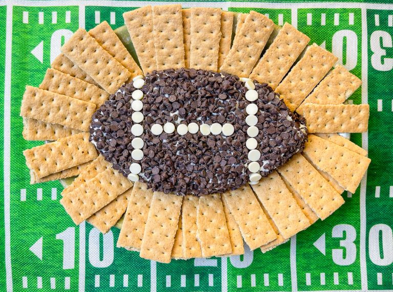 Football Cheesecake Dip is a chocolate chip cheesecake type dip served with graham crackers for dipping. It's a fun and sweet addition to any tailgate table.