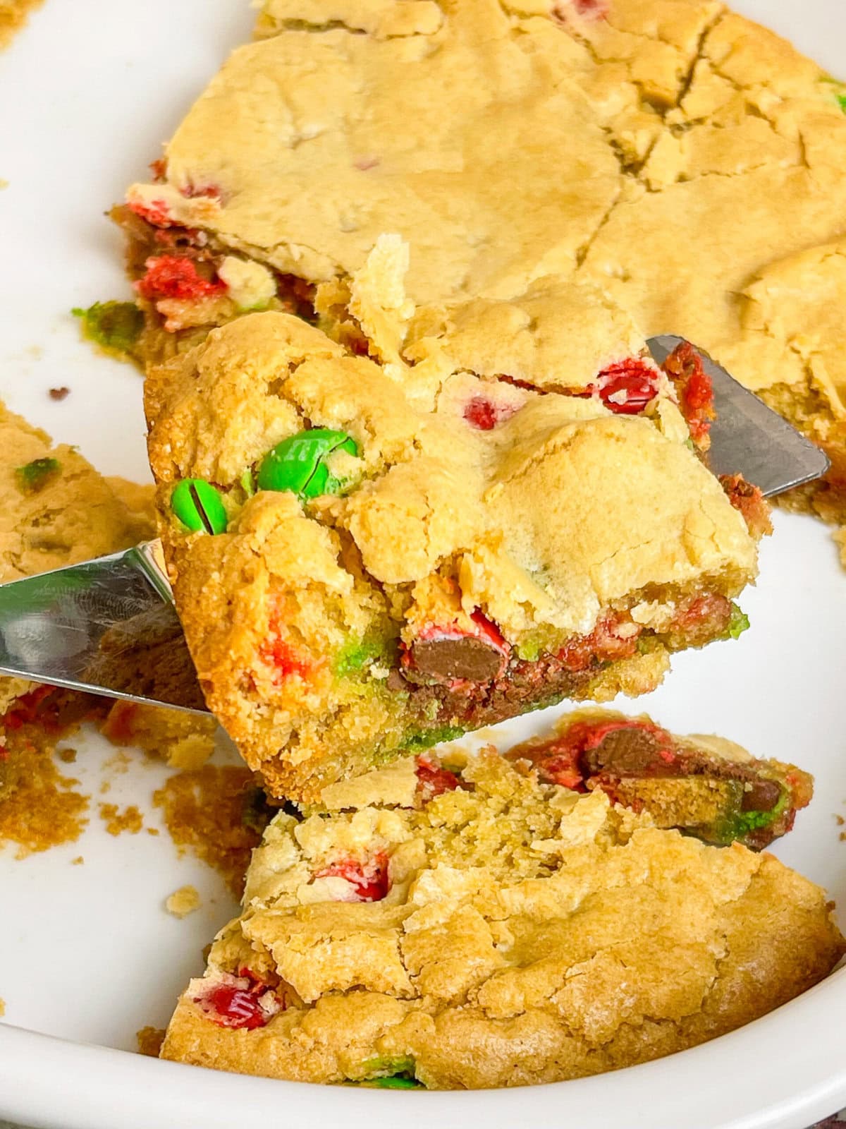 M&M Christmas Cookie Bars are the ultimate holiday treat, combining all the festive fun of Christmas cookies with the ease of a one-pan dessert. These bars are soft, chewy, and bursting with colorful red and green M&M candies. These cookie bars are made with a buttery, golden cookie base and plenty of chocolatey M&M's, these bars are perfect for holiday parties, cookie exchanges, or a cozy night at home with a cup of hot cocoa. Whether you’re baking with kids or whipping up a quick treat for a crowd, these cookie bars are a festive, fuss-free way to spread holiday cheer!