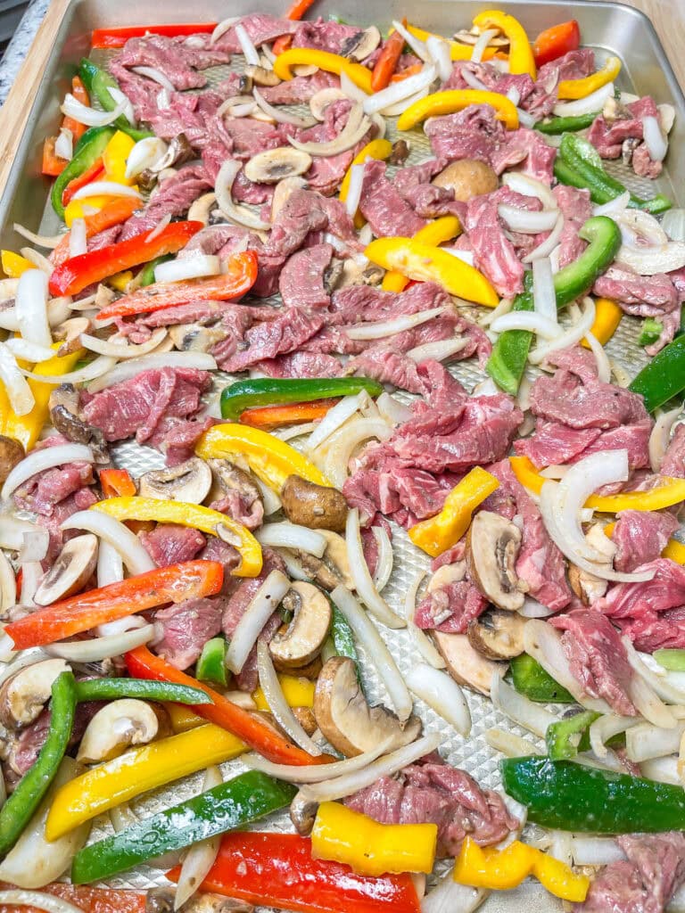 These easy Sheet Pan Cheesesteak Sandwiches are ready in under 30 minutes! A soft bun loaded with marinated beef, bright bell peppers, onions and earthy mushrooms, covered in melty cheese for a flavor packed family dinner.