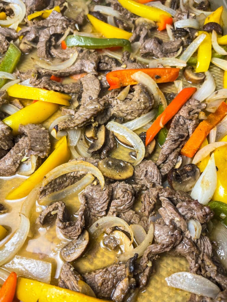 These easy Sheet Pan Cheesesteak Sandwiches are ready in under 30 minutes! A soft bun loaded with marinated beef, bright bell peppers, onions and earthy mushrooms, covered in melty cheese for a flavor packed family dinner.