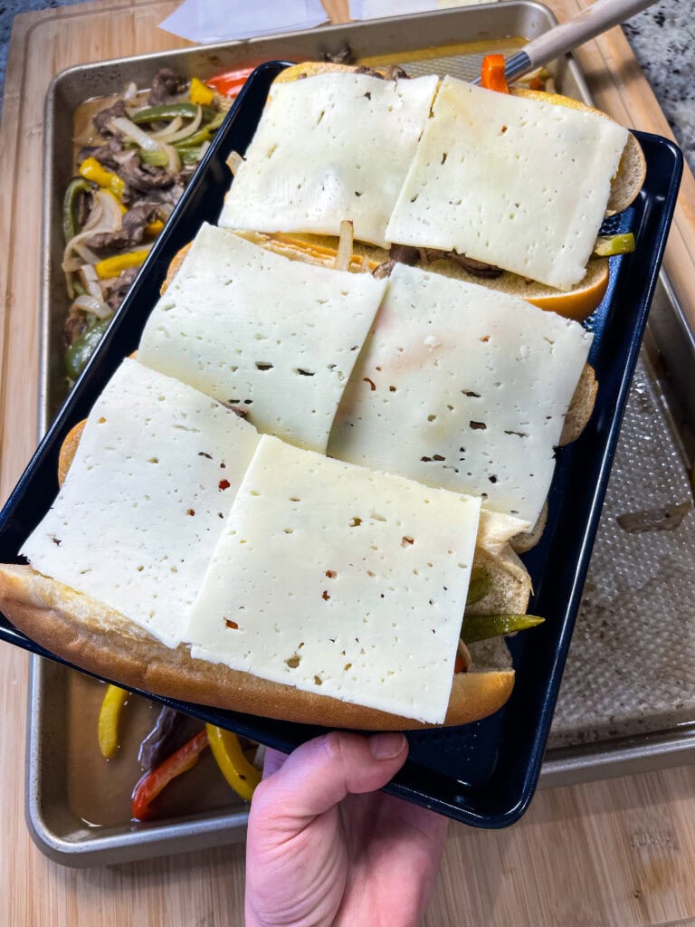 These easy Sheet Pan Cheesesteak Sandwiches are ready in under 30 minutes! A soft bun loaded with marinated beef, bright bell peppers, onions and earthy mushrooms, covered in melty cheese for a flavor packed family dinner.