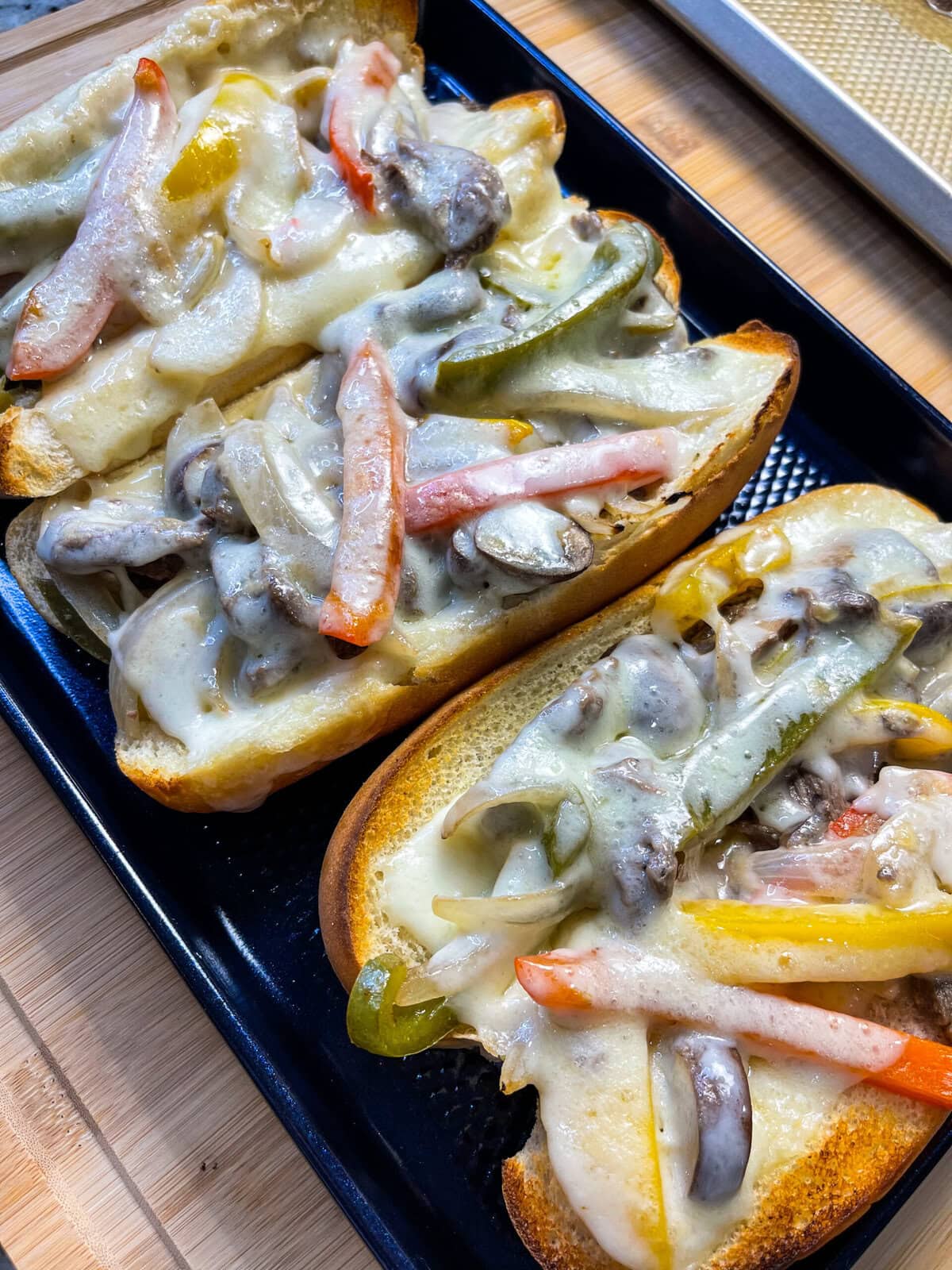 These easy Sheet Pan Cheesesteak Sandwiches are ready in under 30 minutes! A soft bun loaded with marinated beef, bright bell peppers, onions and earthy mushrooms, covered in melty cheese for a flavor packed family dinner.