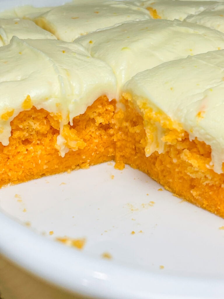 Orange Creamsicle Poke Cake tastes just like the ice cream treat you remember- a bright orange tang along with a creamy vanilla finish. This cake starts with an orange boxed cake mix, studded with creamy orange Jell-o and finished with a citrus orange cream cheese frosting. You'll want to start bringing this dessert everywhere!